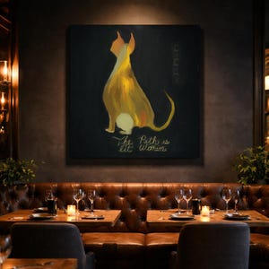 May include: A large square canvas displays a stylized painting of a dog in shades of yellow and orange against a black background. The text "The Path is lit Within" is written in gold script below the dog. The artwork hangs above a leather booth.
