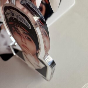 May include: A clear acrylic keychain featuring a printed image of a person with the word "Praying" in a stylized font. The keychain has a silver-colored metal ring.