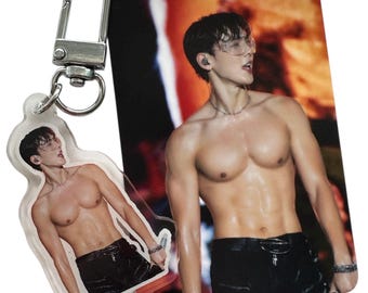 May include: A clear acrylic keychain and a photo card featuring a shirtless person wearing black pants and sunglasses. The keychain has a silver clasp. The photo card has a red and orange background.