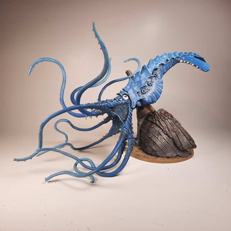 May include: A blue and white painted miniature of a tentacled sea creature with multiple eyes, posed on a rocky base.
