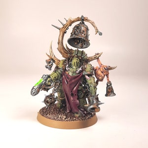 May include: A green and brown painted miniature figure of a Chaos Space Marine with a large bell on a branch, a smaller bell on a chain, and a small, fleshy, pink creature with a bell on its arm.