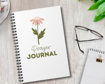 Può includere: Un diario bianco a spirale con un'illustrazione di un fiore rosa e verde e il testo "Prayer Journal" sulla copertina.