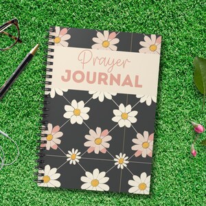 Puede incluir: Un cuaderno de espiral negro y blanco con un patrón floral y el texto "Prayer Journal" en la portada.