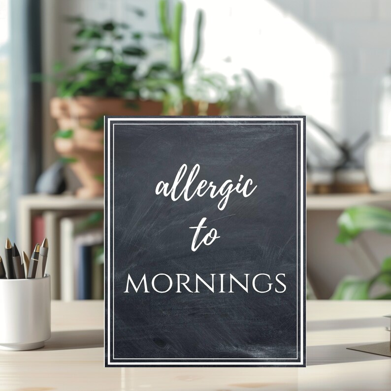 Charming "Allergic to Mornings" printable sign with a rustic chalkboard design. Features elegant white script and serif text on a textured black background with a double-line border. Perfect for home, classroom, or office decor!
