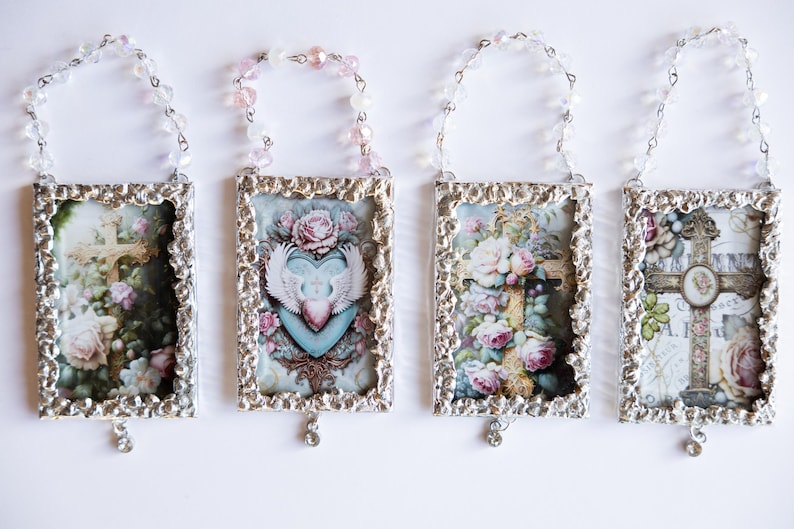 May include: Four silver-toned frames with ornate edges, each containing a different vintage-style image of a cross and flowers. Each frame is hung from a beaded chain with a crystal pendant.