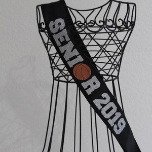May include: Black satin sash with silver glitter lettering that reads "Senior 2019" and a basketball graphic.