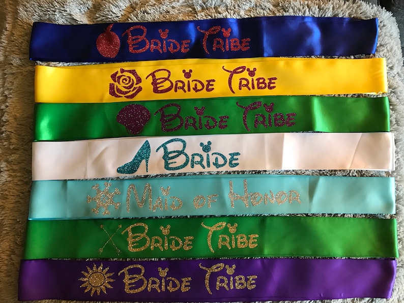 Puede incluir: Siete cintas de sat&eacute;n en varios colores con texto de purpurina dorada que dice "Bride Tribe" y "Maid of Honor".