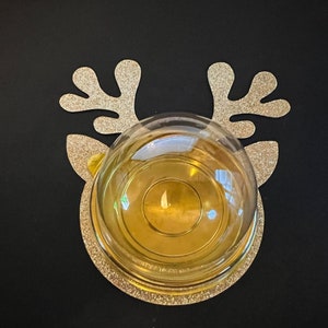 Peut inclure: Ornement en forme de renne en paillettes dor&eacute;es avec un d&ocirc;me en verre transparent sur le dessus. L'ornement est sur un fond noir.