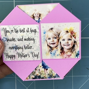 May include: A pink card with a message that reads "You're the best at hugs, snacks, and making everything better. Happy Mother's Day!" The card has a photo of two young girls on the front.