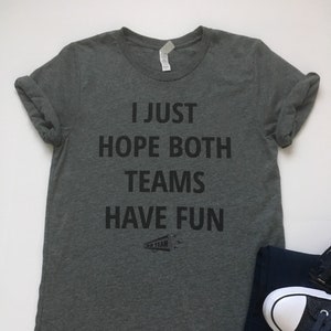 May include: A heather grey t-shirt with the text "I just hope both teams have fun" printed on the front. A small megaphone with the text "Go Team" is printed below the text.
