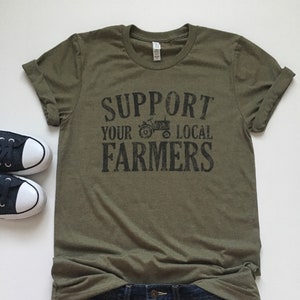 May include: A green t-shirt with the text "Support Your Local Farmers" and a black silhouette of a tractor.