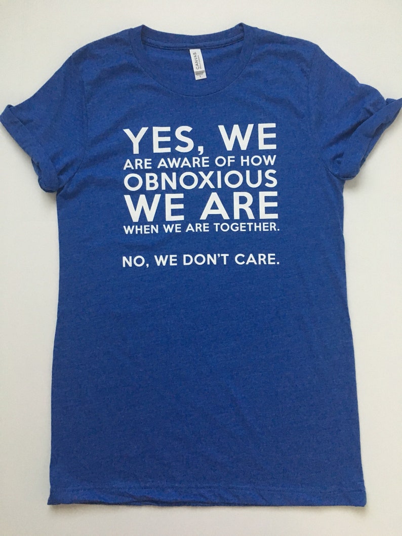 Może przedstawiać: Koszulka w kolorze kr&oacute;lewskiego błękitu z białym nadrukiem: "YES, WE ARE AWARE OF HOW OBNOXIOUS WE ARE WHEN WE ARE TOGETHER. NO, WE DON'T CARE."