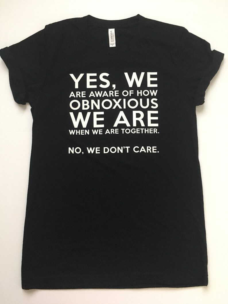 Może przedstawiać: Czarny T-shirt z białym tekstem, kt&oacute;ry brzmi: "YES, WE ARE AWARE OF HOW OBNOXIOUS WE ARE WHEN WE ARE TOGETHER. NO, WE DON'T CARE."