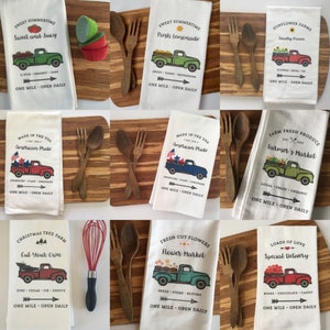 May include: Set of 10 kitchen tea towels featuring vintage pickup trucks with various themes, including "Sweet Summertime", "American Pride", "Farmer's Market", "Christmas Tree Farm", "Flower Market", and "Loads of Love". Each towel has a unique design and text.
