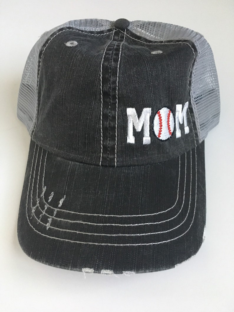 May include: A black and grey baseball cap with a mesh back. The front of the cap has the word "MOM" embroidered in white with a baseball graphic in the "O".
