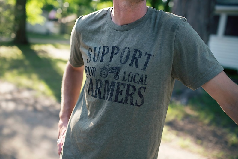 May include: A green t-shirt with a distressed black graphic that says "Support Your Local Farmers" with a small tractor image.