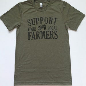 May include: A green t-shirt with the text "Support Your Local Farmers" in black lettering. A black silhouette of a tractor is included in the text.