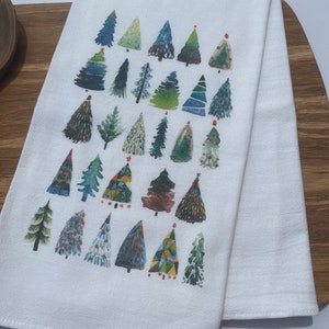 K&ouml;nnte beinhalten: Ein wei&szlig;es K&uuml;chentuch mit einem bunten Muster aus verschiedenen Weihnachtsb&auml;umen. Die B&auml;ume sind in Gr&uuml;n-, Blau-, Rot- und Gelbt&ouml;nen bemalt.