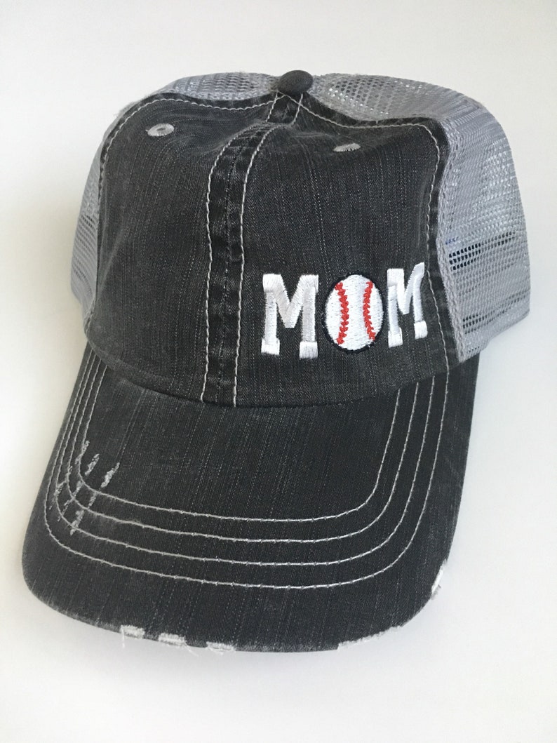 May include: Black and grey baseball cap with a white embroidered baseball and the word "MOM" on the front.