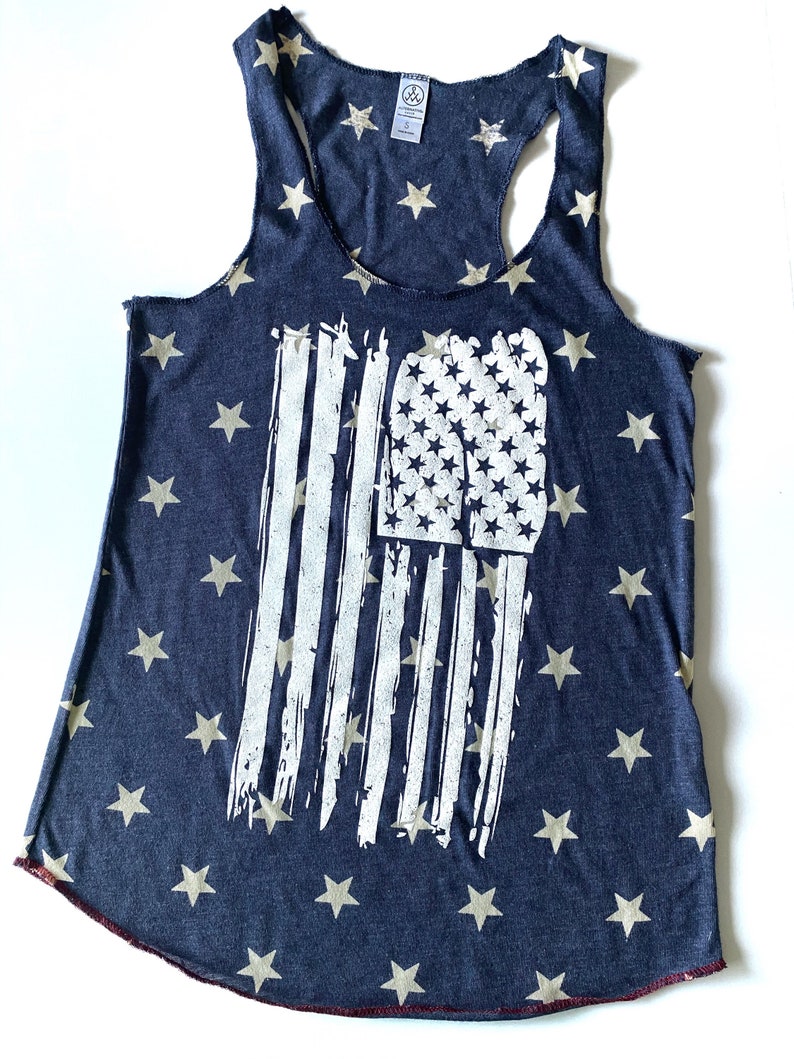 May include: A navy blue tank top with a white distressed American flag design. The tank top is covered in small white stars.