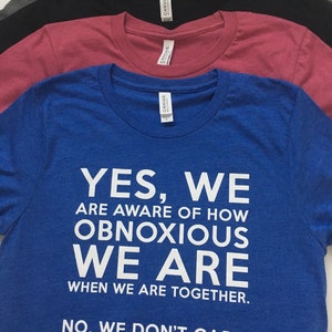 Może przedstawiać: Niebieska koszulka z białym nadrukiem: "YES, WE ARE AWARE OF HOW OBNOXIOUS WE ARE WHEN WE ARE TOGETHER. NO, WE DON'T CARE."