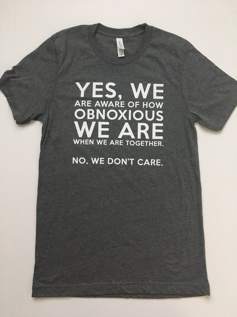 Może przedstawiać: Szary t-shirt z białym nadrukiem, kt&oacute;ry brzmi: "YES, WE ARE AWARE OF HOW OBNOXIOUS WE ARE WHEN WE ARE TOGETHER. NO, WE DON'T CARE."