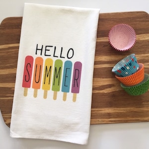 May include: White kitchen towel with the text "HELLO SUMMER" printed in black. The text is surrounded by six colorful popsicle illustrations.