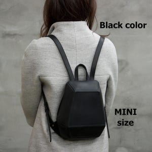 May include: A black mini backpack with a geometric design. The backpack has a top handle and adjustable straps. The text "Black color" and "MINI size" are visible in the image.