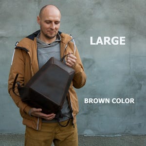May include: A large, brown backpack with a structured design. The bag has a top handle and adjustable straps. The text "LARGE" and "BROWN COLOR" are visible in the image.