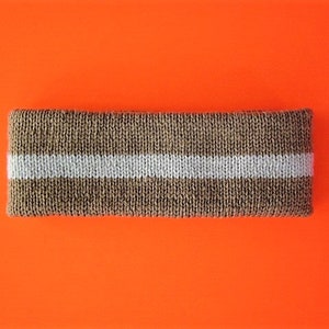 Op de afbeelding: Een bruin gebreid hoofdband met een witte streep.