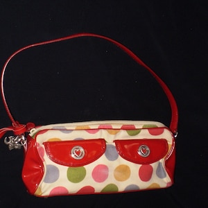 May include: A red and white polka dot handbag with a red patent leather flap and a silver heart charm.