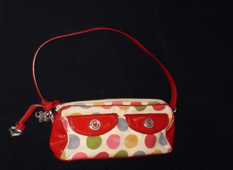 May include: A red and white polka dot handbag with a red patent leather flap and a silver heart charm.