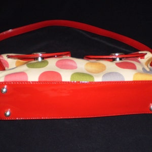 May include: A red patent leather handbag with a cream canvas body featuring a multi-coloured polka dot pattern.