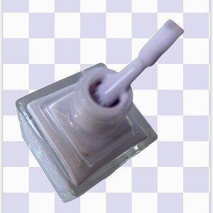 Peut inclure: Un flacon de vernis &agrave; ongles de couleur lilas clair dans un flacon en verre transparent avec un applicateur en brosse blanche.