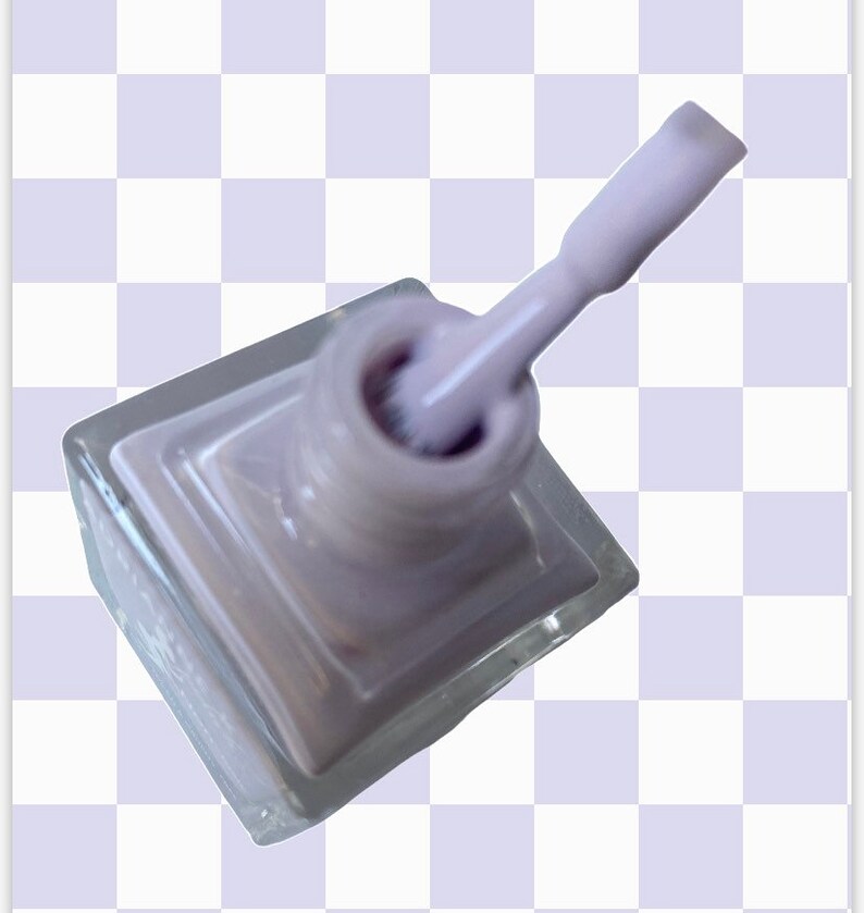 Peut inclure: Un flacon de vernis &agrave; ongles de couleur lilas clair dans un flacon en verre transparent avec un applicateur en brosse blanche.