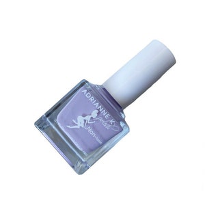 Peut inclure: Un flacon carr&eacute; de vernis &agrave; ongles violet clair avec un bouchon blanc. Le flacon porte une &eacute;tiquette indiquant "Adrianne K polish" et "Non-toxique".