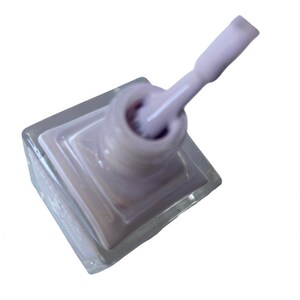 Peut inclure: Un flacon de vernis &agrave; ongles de couleur lilas clair dans un flacon en verre transparent avec un applicateur en brosse blanche.