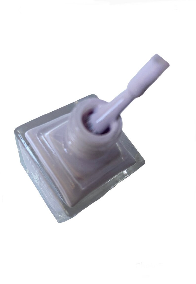 Peut inclure: Un flacon de vernis &agrave; ongles de couleur lilas clair dans un flacon en verre transparent avec un applicateur en brosse blanche.