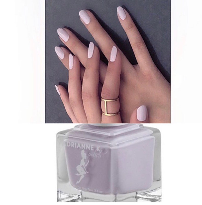 Peut inclure: Un flacon de vernis &agrave; ongles de couleur lilas clair avec le nom de la marque "Drianne K Polish" sur l'&eacute;tiquette. Le flacon est de forme carr&eacute;e et poss&egrave;de un bouchon en verre transparent.