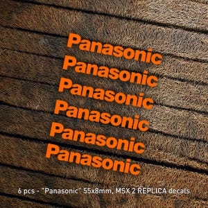 May include: Six orange "Panasonic" decals, each measuring 55 by 8 millimeters. The decals are arranged vertically on a brown, textured surface. The text "6 pcs - "Panasonic" 55x8mm, MSX 2 REPLICA decals" is visible at the bottom of the image.