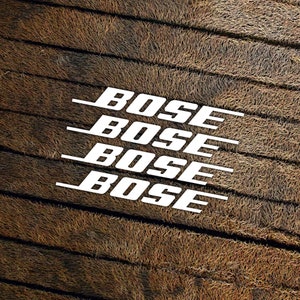 May include: Four white "BOSE" logos stacked on top of each other on a brown, textured background.