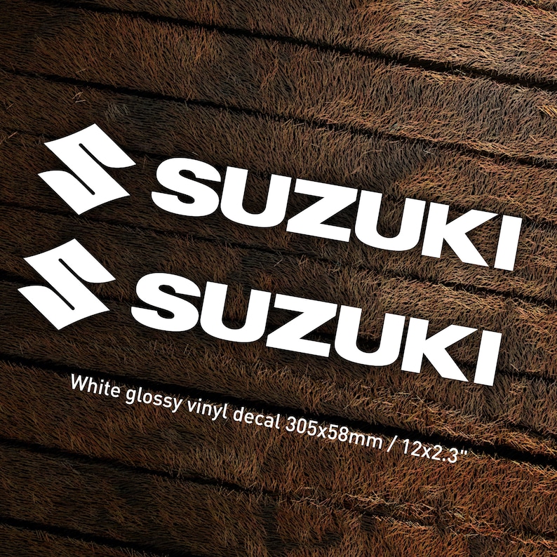 May include: Two white glossy vinyl decals with the word "SUZUKI" in a bold white font. The decals are 12 inches by 2.3 inches.