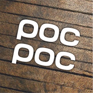 以下が含まれることがあります： 茶色の木製の背景に、白い文字「POC」が2つ重ねられています。