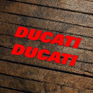 May include: The word "DUCATI" is written twice in red letters on a brown, textured background.