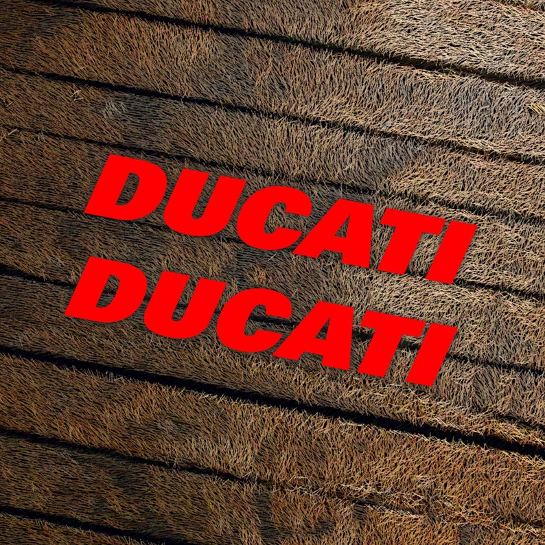 May include: The word "DUCATI" is written twice in red letters on a brown, textured background.