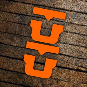 Puede incluir: Tres calcomanías de vinilo naranja en forma de la letra "U" dispuestas verticalmente. Las calcomanías están sobre una superficie de madera marrón.