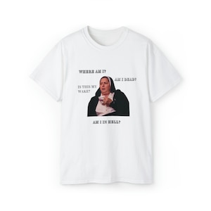 May include: White t-shirt with a printed image of a woman in a nun's habit holding a cup of tea. The text on the shirt reads "Where am I? Is this my wake? Am I dead? Am I in hell?"