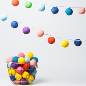 May include: A wire string of colorful cotton ball lights with a basket full of multi-colored cotton balls.