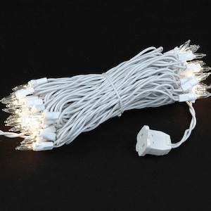 May include: A string of 50 white mini lights with clear bulbs. The lights are strung on white wire and have a white plug.