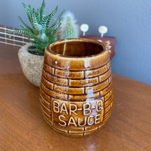 May include: Brown ceramic jar with a brick pattern and the words "BAR-B-Q SAUCE" on the front.